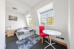 1 dormitorio con cama, escritorio y mesa en Barnet Serviced Accommodation - Elegant 5-Bedroom Home, Just a 7-Minute Stroll from High Barnet Station - Book Your Stay Today!", en New Barnet