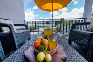 Una cesta de fruta y jugo en una mesa en un balcón. en Azores Palmeira Villa, en Ponta Delgada