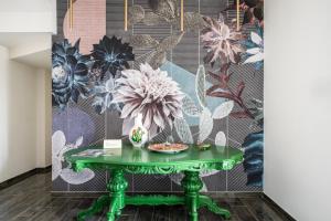 zielony stół przed ścianą z malowidłem kwiatowym w obiekcie Fiko Suite w mieście Roccella Ionica