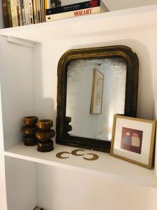 a mirror on a shelf with a picture and some books at Gîte des Canelles in Villespy