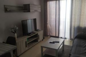 ein Wohnzimmer mit einem Flachbild-TV und einem Tisch in der Unterkunft Apartamento nuevo con piscina y amplio balcon in Sant Carles de la Ràpita