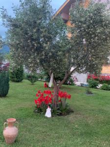 a statue of a girl in front of a tree and red flowers at Hotel Villa Linda in Shkodër