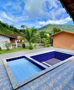 uma piscina com piso de azulejo azul e uma casa em Pousada Pedra Grande - SANA em Macaé
