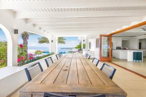 ein langer Holztisch und Stühle in einem Raum mit Blick auf das Meer in der Unterkunft Exclusive 10-Guest Seaview Villa in Gated Community with Pool & Private Beach Access in Willibrordus