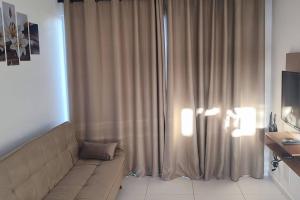 a living room with a couch in front of a curtain at Casa Aconchegante B in Guanamby