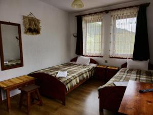 een kamer met 2 bedden, een tafel en een spiegel bij Къща за гости Чаршията in Smolyan