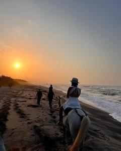 pessoas a cavalo na praia ao pôr do sol em Sierra Sagrada Tayrona em Guachaca