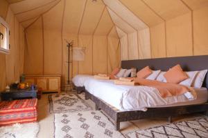 a bedroom with a large bed in a tent at Camel Trips Luxury Camp in Merzouga