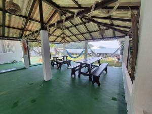 eine Terrasse mit Picknicktischen und Bänken in einem Gebäude in der Unterkunft Maravilha das Estrelas in Angra dos Reis