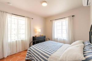 a bedroom with a bed and two windows at Cute & Cozy 2BR 1BA Adobe w Firepit Near UA & UMC, Low Summer Rates! in Tucson