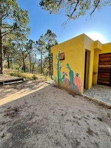 Camping en la Sierra de Arteaga في Los Lirios: منزل اصفر وعليه لوحه
