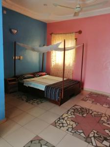1 dormitorio con 1 cama en una pared de color rosa en CHEZ ALFA, en Jugu