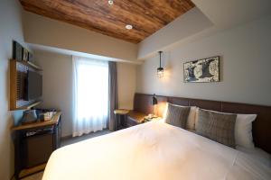 a bedroom with a large white bed with a window at Hotel Resol Akihabara in Tokyo