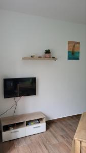 sala de estar con TV de pantalla plana en una pared blanca en Apartman Padova, en Rab