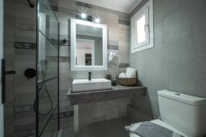 ein Badezimmer mit einem Waschbecken, einem Spiegel und einem WC in der Unterkunft Leonidas Resort in Ermioni