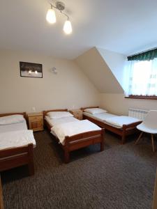 een kamer met drie bedden en een tafel erin bij Willa Gorce in Ostrowsko