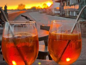 two glasses of drinks sitting on a table with the sunset in the background at Pension zum goldenen Anker in Wittenberge