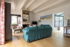 een woonkamer met een blauwe bank en een open haard bij ILE DE RÉ - Villa Sylvabelle in La Flotte