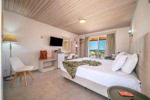 Schlafzimmer mit einem Bett, einem Schreibtisch und einem TV in der Unterkunft Leonidas Resort in Ermioni