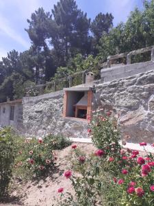 a stone building with a window and flowers at Casa das Leiras in Loivos da Ribeira
