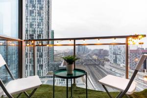a balcony with chairs and a table and a view of a city at SkyHigh Haven LED-Lit Downtown Condo Retreat in Toronto