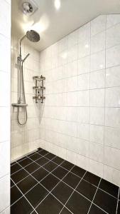 La salle de bains est pourvue d'une douche et de carrelage noir. dans l'établissement Superhomes, à Göteborg