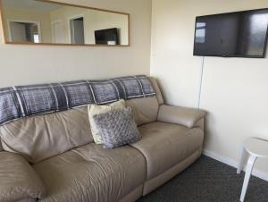a brown couch in a room with a mirror at Hemsby Holiday Home - Norfolk beach & seaside fun in Great Yarmouth