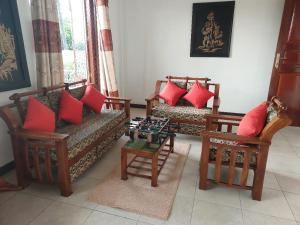 a living room with couches and chairs with red pillows at Ayansa in Homagama