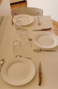 a table with white plates and glasses and utensils at Calanques Prado Stade et Parking in Marseille