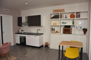 a kitchen with white cabinets and a table and yellow chairs at Residence Diamante in Villorba