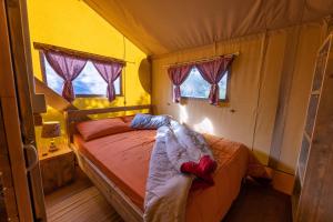 a bedroom with a bed in a room with windows at Il Pruno - Luxury Tent in San Giuliano Terme