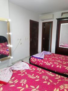 a bedroom with two beds and a mirror at شاليه غرفة ورسيبشن وحمام ومطبخ عماره 6 الدور الثاني 6232 in Port Said