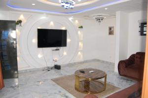 uma sala de estar com uma televisão e uma mesa de centro em Les Résidences Oluwa Sheyi em Cotonou