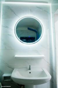 uma casa de banho com um lavatório branco e um espelho. em Les Résidences Oluwa Sheyi em Cotonou