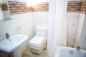 ROSES REGENCY HOTEL AND SUITES في أبوجا: حمام به مرحاض أبيض ومغسلة