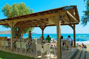 a group of people sitting at tables on the beach at Faros Vetoula Suites in Stalos