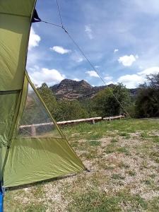 una tenda verde in un campo con una montagna sullo sfondo di El Rebost de Penyagalera a Beceite