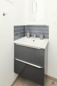 La salle de bains est pourvue d'un lavabo blanc et de carrelage bleu. dans l'établissement La résidence Jeanne d'Arc 1 , Troyes - France, à Troyes