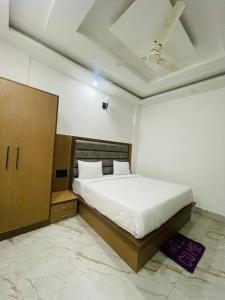 Hotel City Star Family Stay في ماثورا: غرفة نوم بسرير أبيض وخزانة خشبية
