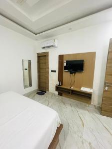 une chambre d'hôtel avec un lit et une télévision dans l'établissement Hotel City Star Family Stay, à Mathura