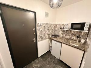 een kleine keuken met een zwarte deur en een wastafel bij Luna Apartament in Timişoara