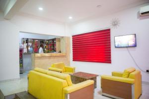 ROSES REGENCY HOTEL AND SUITES في أبوجا: غرفة معيشة مع كراسي صفراء ونافذة حمراء