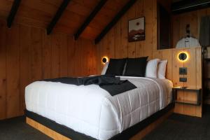 a bedroom with a large white bed with wooden walls at Alto's Gardens in Fortuna