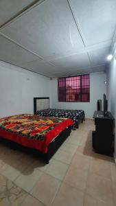 een slaapkamer met 2 bedden en een televisie. bij Hostal las flores de Valledupar in Valledupar