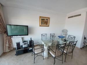 een eetkamer met een tafel en stoelen en een televisie bij Maison pied dans l'eau à résidence Jinène Hammamet in Hammamet