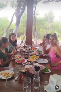 Un gruppo di persone seduti intorno a un tavolo che mangiano cibo di ida bay doğa evleri a Edremit