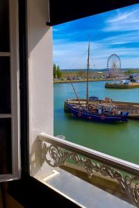 - une vue sur un bateau dans l'eau depuis une fenêtre dans l'établissement Best Western Le Cheval Blanc -Vue sur le port-plein centre ville, à Honfleur