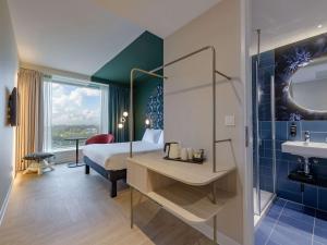 een slaapkamer met een bed en een badkamer met een wastafel bij ibis Styles Rotterdam Ahoy in Rotterdam