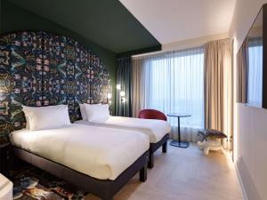 a hotel room with two beds and a large window at ibis Styles Rotterdam Ahoy in Rotterdam