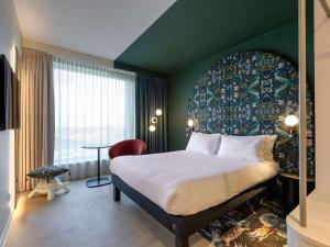 una habitación de hotel con una cama grande y una mesa en ibis Styles Rotterdam Ahoy, en Róterdam